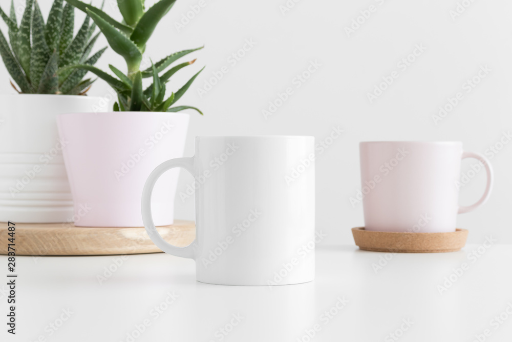 White mug mockup with various types of succulent plants on a white table.