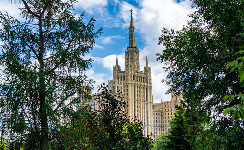 View from territory of Moscow zoo on residential building among foliage of trees. High-rise building on Kudrinskaya Square one of seven Stalinist high-rise buildings . Moscow, Russia, June, 2019. 