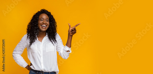 Cheerful black girl pointing at empty space