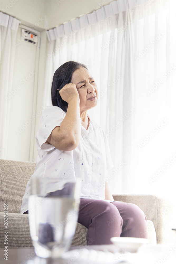 old age, health problem, vision and people concept - close up of Asian senior woman sitting on sofa and having headache at home.She may had Headache Symptoms.She looks pain and sick old age, health problem, vision and people concept - close up of Asian senior woman sitting on sofa and having headache at home.She may had Headache Symptoms.She looks pain and sick