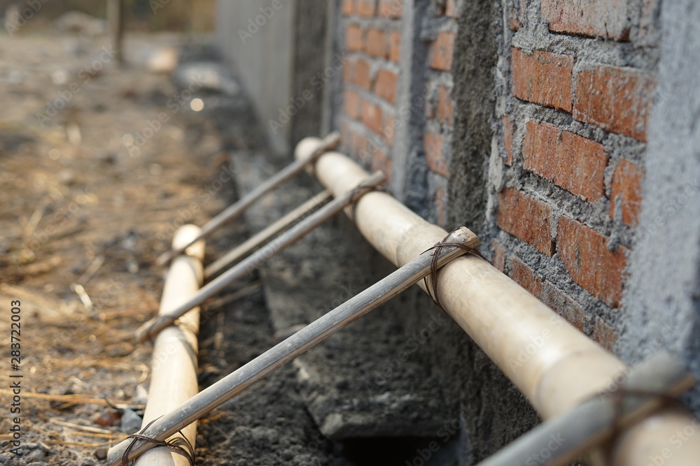 Strong bamboo ladder lay in under construction house beside brick wall Strong bamboo ladder lay in under construction house beside brick wall