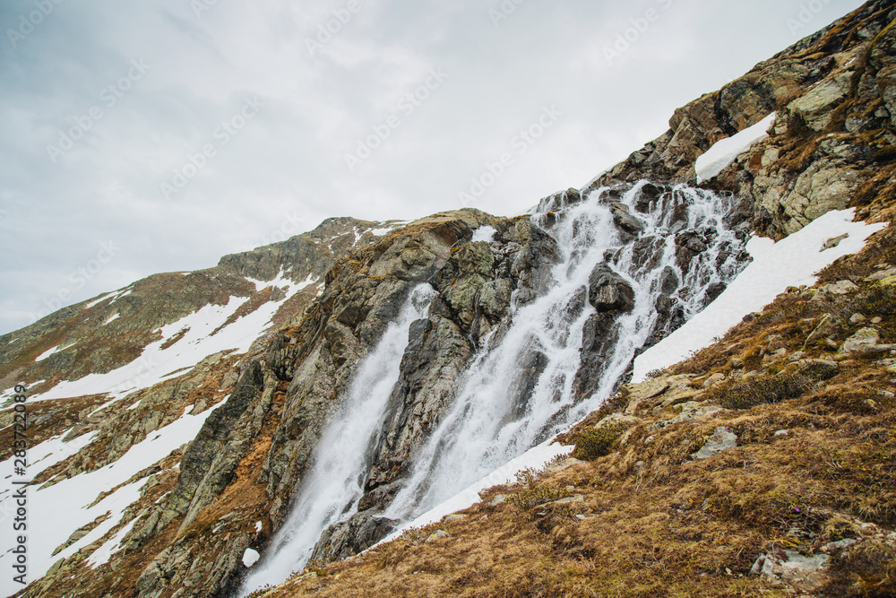 Alpine waterfall in mountain. Alps. Snow. Poster Image. Trekking. Alpine waterfall in mountain. Alps. Snow. Poster Image. Trekking.
