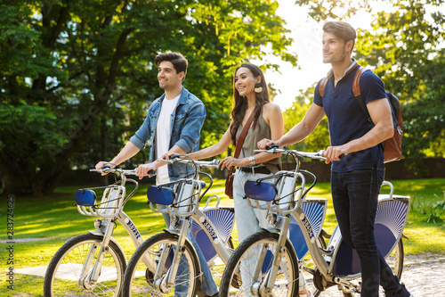 Group of happy friends riding bicycles at the park
