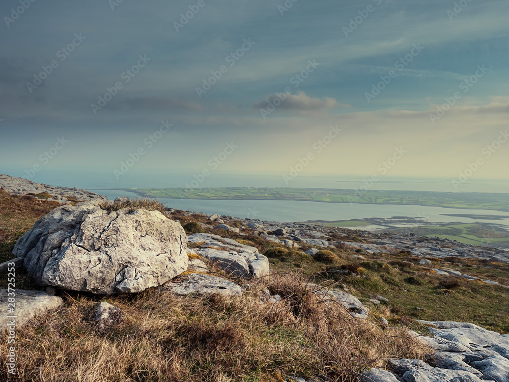 Burren National park, View from a mountain on Galway bay, Calm cloudy sky, Rough terrain and big stones in foreground. Concept travel, hiking, Burren National park, View from a mountain on Galway bay, Calm cloudy sky, Rough terrain and big stones in foreground. Concept travel, hiking,