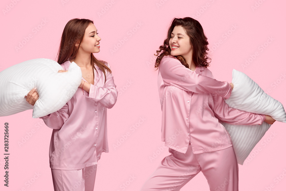 Teenagers in pajamas fighting with pillows Teenagers in pajamas fighting with pillows