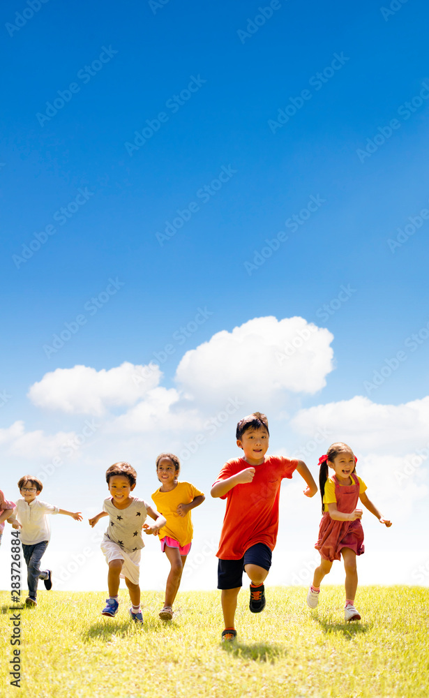 Multiethnic group of school children running on the grass Multiethnic group of school children running on the grass