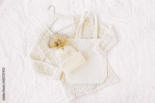 Knitted white sweater with hat and tote bag. Autumn/winter fashion clothes collage on white background. Top view flat lay.