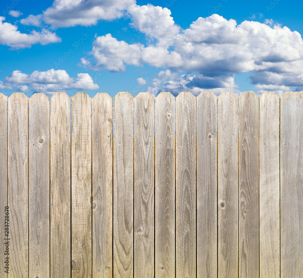 Whitewashed rustic wood privacy fence with blue sky and clouds Whitewashed rustic wood privacy fence with blue sky and clouds
