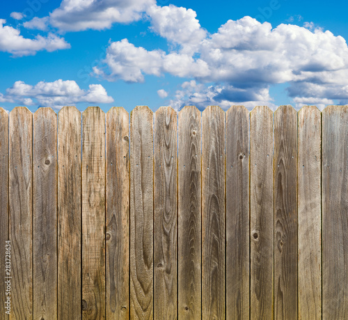 Rustic wooden fence with blue sky and clouds