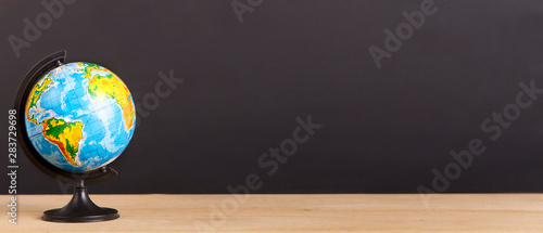 World globe on desk over chalkboard background photo