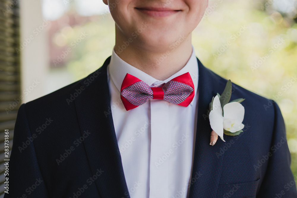 Fototapeta premium Wedding fashion for men. Closeup of caucasian man put wearing stylish suit and shirt decorated with a boutonniere.