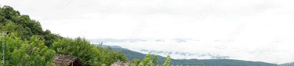 panoramic view of mountains and the abstract fog on the sky, forested mountain slope in low lying cloud with the wooden bamboo hut.