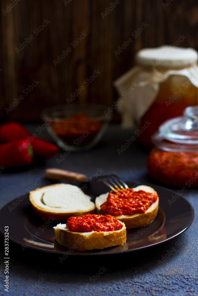 ajvar, appetizer of baked peppers on the table, bread with ajvar, toast with ajvar, balkan appetizer of baked peppers, vertical, space for your text