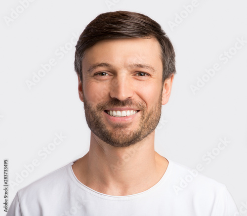 Positive Charismatic Man Smiling At Camera Over White Background