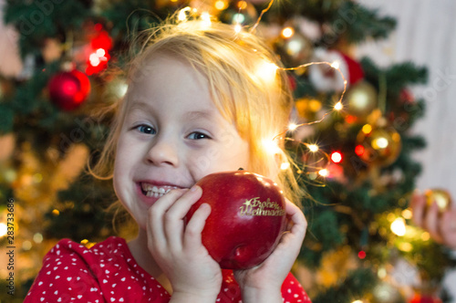 little cheerful girl holding a christmas apple.