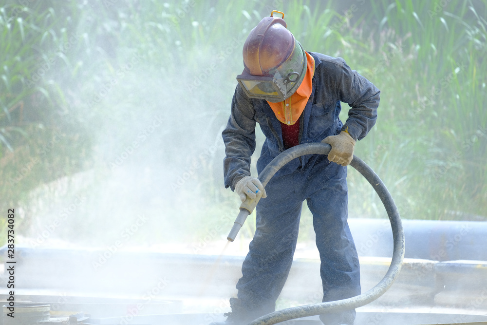 Worker is remove paint by air pressure sand blasting Worker is remove paint by air pressure sand blasting