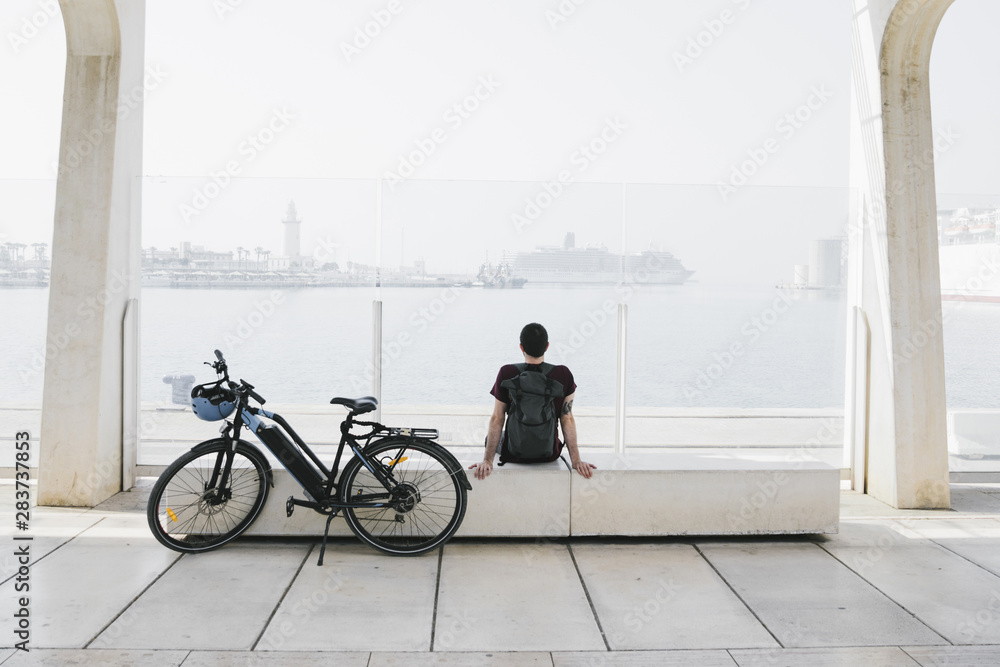 Long shot e-bike next to relaxin man on bench - obrazy, fototapety, plakaty 