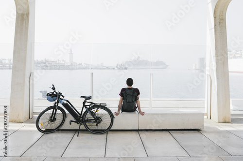 Long shot e-bike next to relaxin man on bench