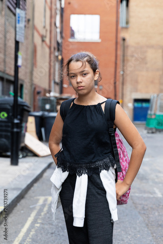 Portrait of a young girl in an alley full of garbage