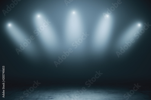 Abstract empty stage with grey smoky spotlights and concrete floor in dark room.