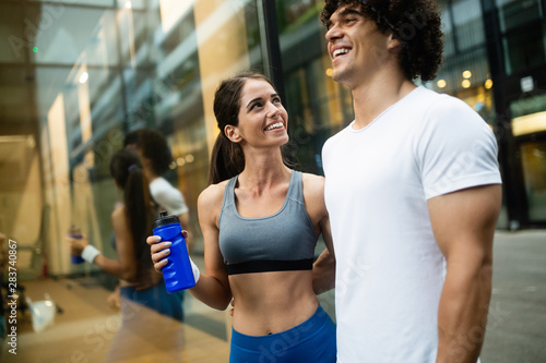 Young man and woman having break after running workout and drinking water