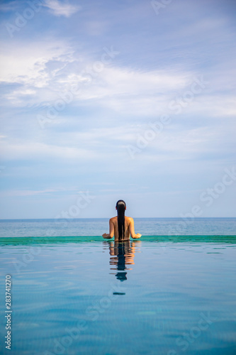 Woman relaxing in infinity swimming pool with sea view, vacation in tropics © dtatiana