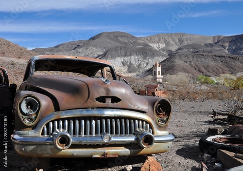 Rusty old car near mountains and desert. old tower in the background. national park Death Valley