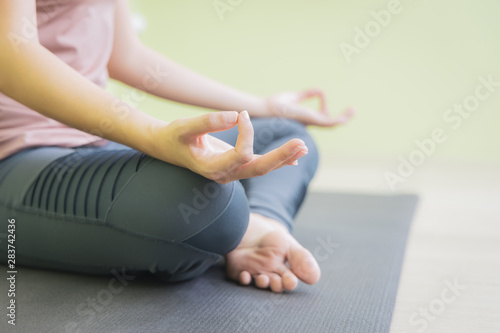 Close up woman hand doing yoga in lotus pose in studio, sitting on black mat, side view.