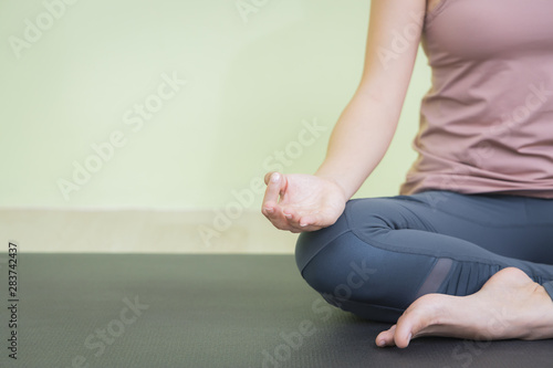 Close up woman hand doing yoga in lotus pose in studio, sitting on black mat, with copy space.
