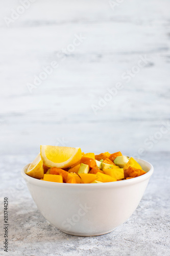 Pegan salad with mango, avocado and sweet potatoes, served with lemon water. Paleo diet. Pegan diet. Vegetarian food. Light background