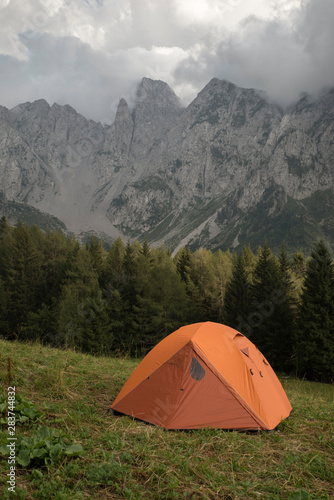 Beautiful early morning camping view. Dolomites mountain sunrise landscape with an orange trekking tent