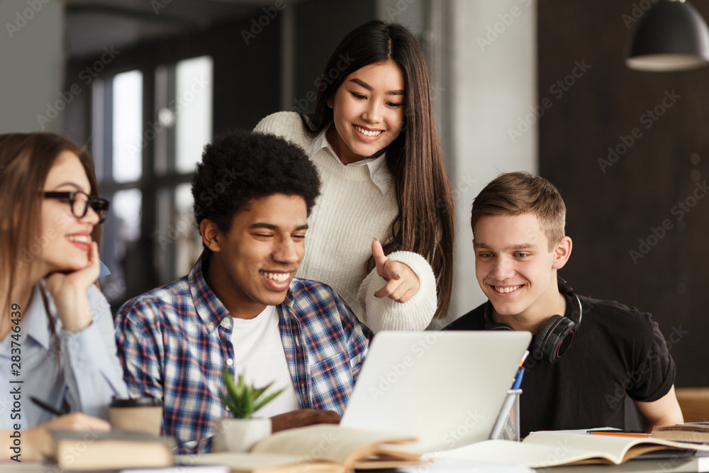 College students using laptop in library, studying together College students using laptop in library, studying together