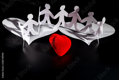White origami people are flying on the red hearts white origami wings. International Human Solidarity Day