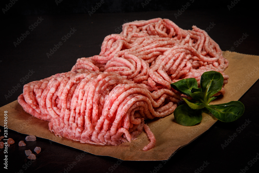 Obraz premium closeup raw minced meat on craft paper with spices and basil