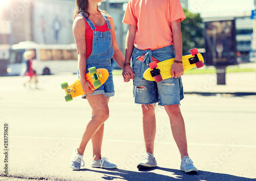 summer, relations, extreme sport and people concept - close up of happy teenage couple with short modern cruiser skateboards on city street