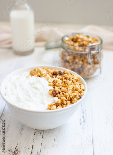 Bowl of Homemade granola with Greek yogurt on a light background. Ingredients for a healthy breakfast - granola and milk. Close-up