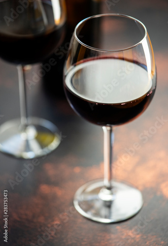 Red wine in a glass, close-up, selective focus. A bottle of red wine and two glasses on the table. Vertical