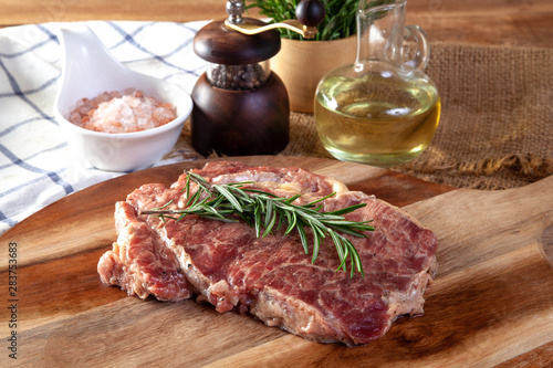 Fresh steak on a wooden cutting board with ingredients