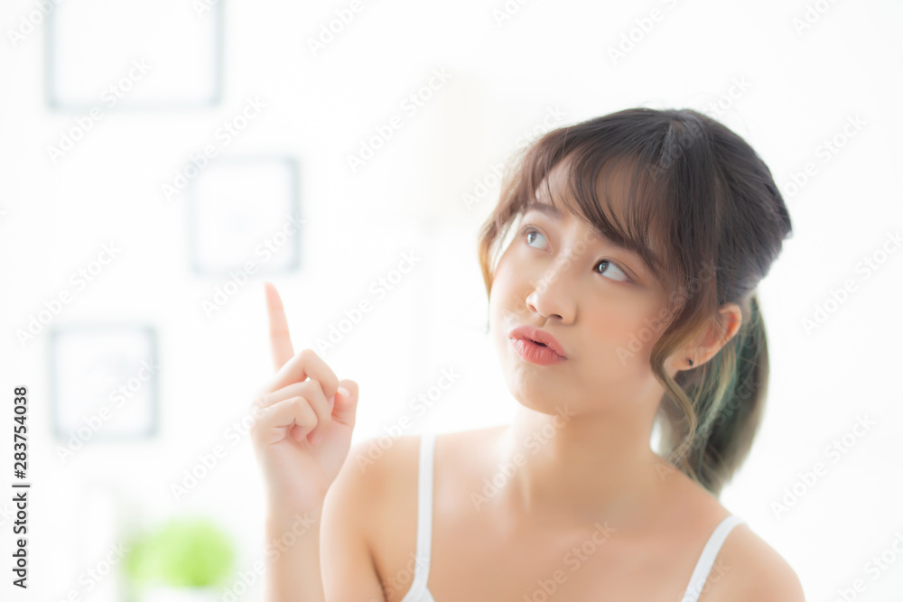 Beautiful portrait young asian woman smiling healthy and wellness at room, beauty asia girl having idea presenting and pointing something skin care and makeup cosmetic, lifestyle concept.