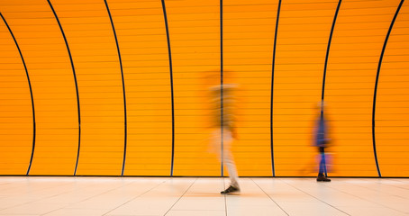 People rushing through a subway corridor (motion blur technique is used to convey movement)