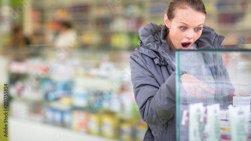 Photography Young woman looking for the right pills/her prescription in a modern pharmacy -d