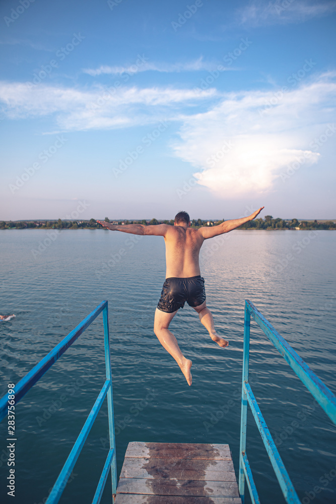 man jumping from tower at lake water on sunset