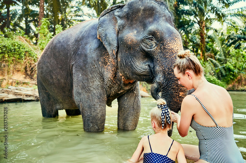 Canvas Print Mother and daughter washing an elephant at an animal sancturay