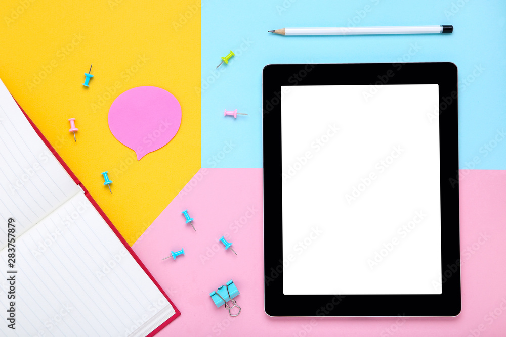 Tablet computer with office supplies on colorful paper background Tablet computer with office supplies on colorful paper background
