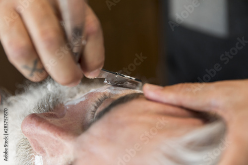 Hairdresser cutting beard with razor to client © Freepik