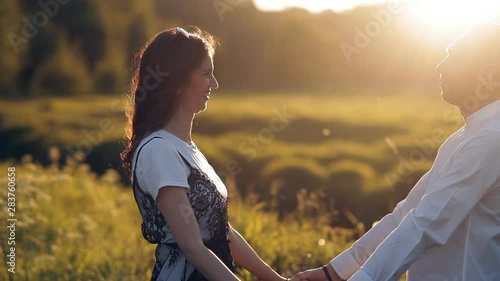 Young man and woman strolling in a meadow at sunset in summer. Romance. Summer love togetherness joy romantic memories forever together concept