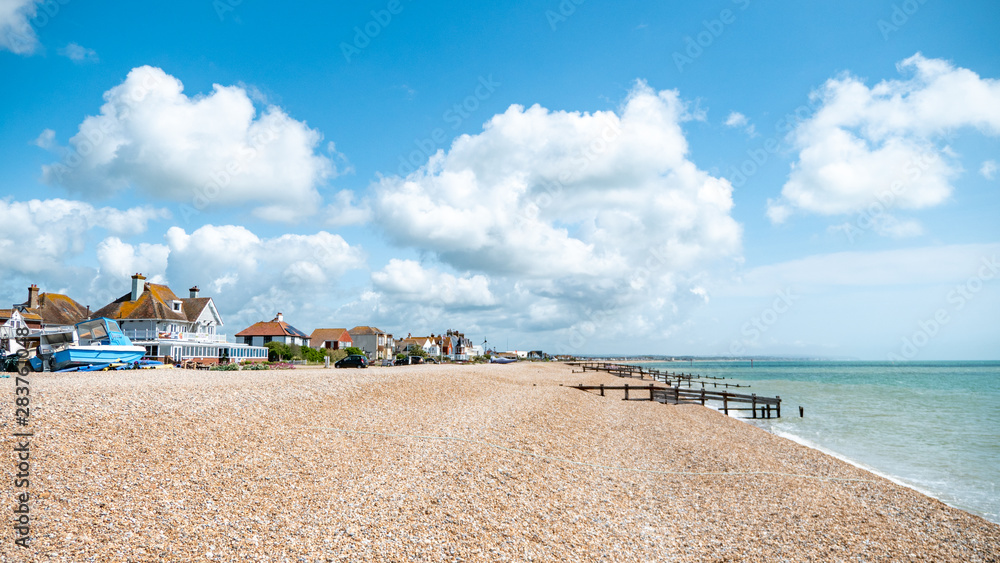 Pevensey Bay, East Sussex, England. Traditional beach houses along the coastline of the south coast of England on a bright summers day.