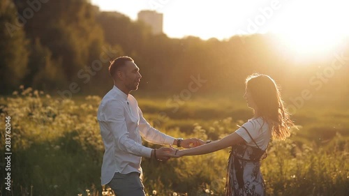 Young man and woman strolling in a meadow at sunset in summer. Romance. Summer love togetherness joy romantic memories forever together concept