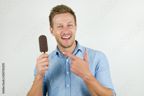 handsome young man points at tasty chololate ice-cream with his finger on isolated white background