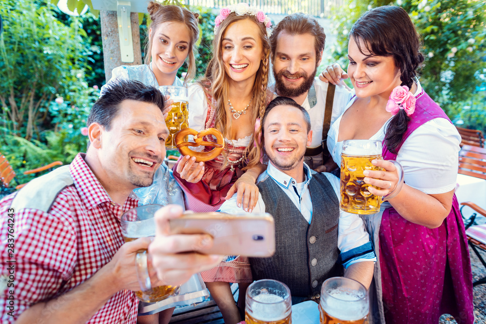 Obraz premium Cheerful group of friends taking a selfie in Bavarian beer garden